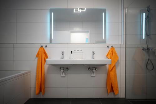 Premium Apartments Monterra في Petschnitzen: حمام أبيض مع حوض ومرآة