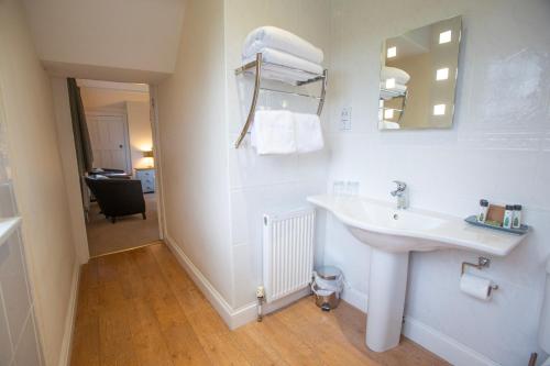 Baño blanco con lavabo y espejo en Little Court, en Charminster
