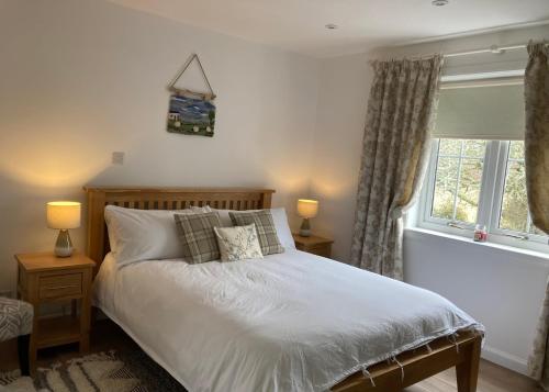 a bedroom with a bed and two lamps and a window at Clashmore Wood in Dornoch