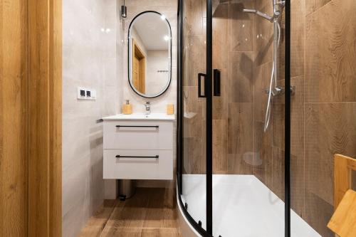 une salle de bains avec douche, lavabo et miroir dans l'établissement Mieszkanie Jagiellońska Kładka przy Morzu i PKP, à Kołobrzeg
