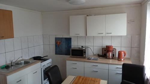 a kitchen with white cabinets and a sink and a microwave at Dreiseithof bei Luckenwalde in Schönefeld