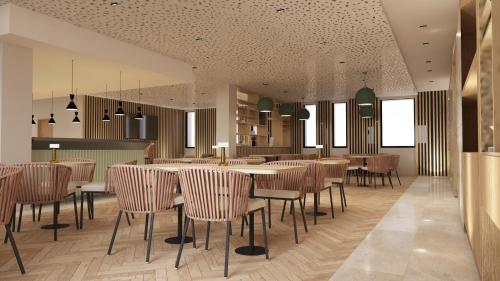 um restaurante com mesas e cadeiras num quarto em Bô Hôtels Ambronay em Ambronay