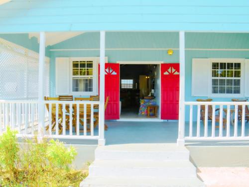 una casa con puertas rojas y porche en Endless Summer Beach House 3BR with Car, en Christ Church