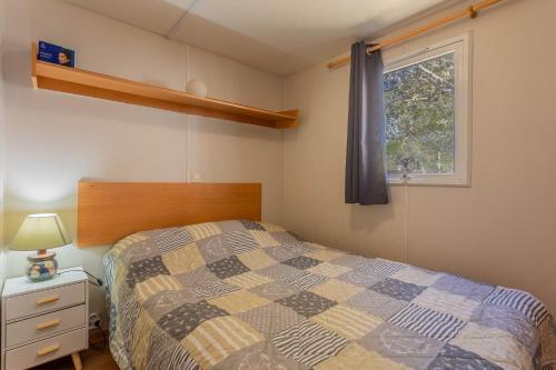 um quarto com uma cama e uma janela em Logement camping Oasis em Puget-sur Argens
