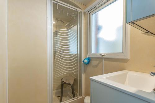 uma casa de banho com uma cabina de duche em vidro e um lavatório. em Logement camping Oasis em Puget-sur Argens