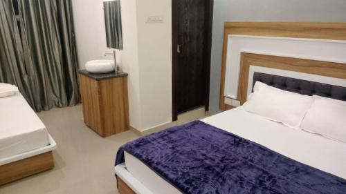 a bedroom with a bed with a purple blanket at Hotel Sai Maa in Shirdi