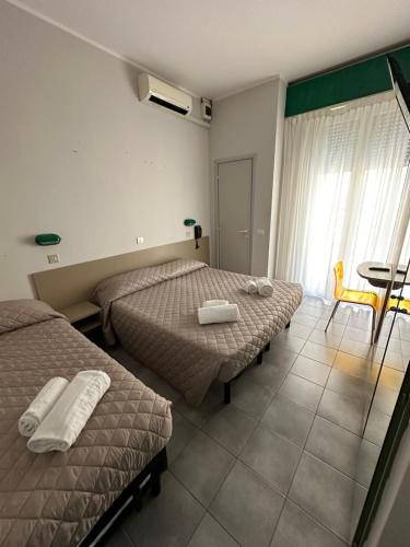 um quarto de hotel com duas camas e uma mesa e uma janela em Hotel Austria em Rimini