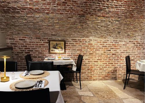a dining room with two tables and a brick wall at Hotel Malleberg in Bruges