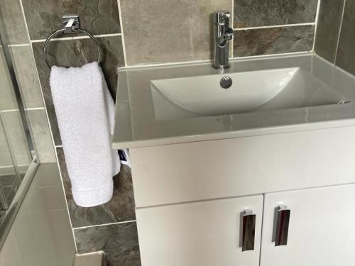baño con lavabo blanco y toalla en Cradle Mount Hotel, en Krugersdorp