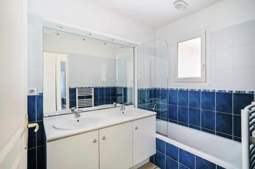 un bagno con un lavandino, uno specchio e una vasca di Appartement 2 pièces Plus, proche de la plage a Soulac-sur-Mer