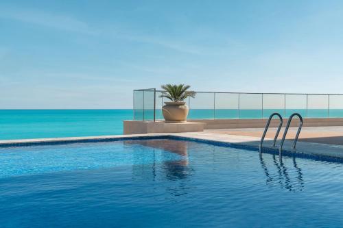 a swimming pool with a view of the ocean at Rixos Premium Alamein in El Alamein
