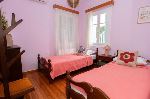 Habitación con 2 camas, paredes de color rosa y suelo de madera. en Aggire Zante Retro Residence, en Zakynthos