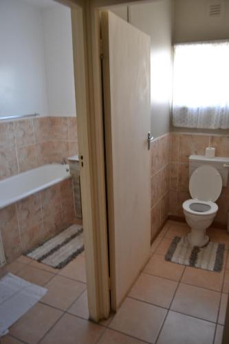 a bathroom with a toilet and a bath tub at Bets Guesthouse in Gariepdam