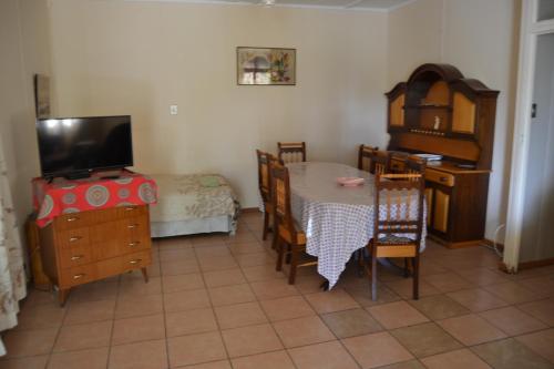 a living room with a dining room table and a television at Bets Guesthouse in Gariepdam