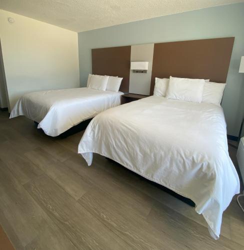 2 camas en una habitación de hotel con sábanas y almohadas blancas en My Home at Columbus, en Columbus
