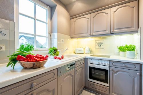 uma cozinha com armários brancos e uma tigela de tomates em Heefwai 2 W6 em Morsum