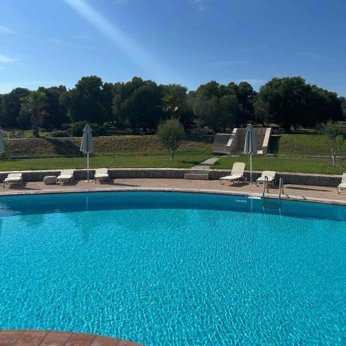 a large blue swimming pool with chairs and umbrellas at VILLAGE CLUB 27 in Nea Fokea