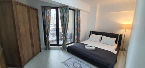 um quarto com uma cama e uma grande janela em Solid Residence Lake Boutique Apartment 11 em Mamaia