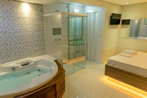 1 cama y baño con lavabo y ducha. en Bluh Motel, en Curitiba