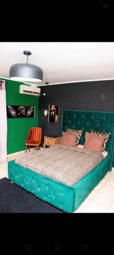 a bedroom with a green bed with a green headboard at Villa Raissa 2 in Libreville