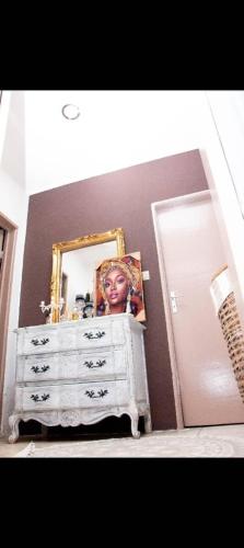 - une commode avec un miroir et une photo d'une femme dans l'établissement Villa Raissa 2, à Libreville