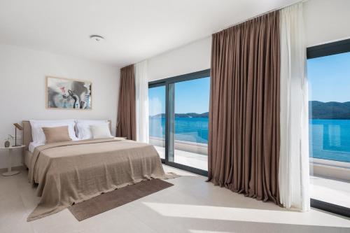 een slaapkamer met een bed en grote ramen bij Villa Maris, 10m from beach, infinity pool in Kučište