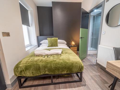 a bedroom with a bed with a green blanket at Cosy retreat Pass the Keys in Beeston