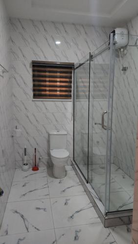 a bathroom with a glass shower and a toilet at MeTime Residence Enugu in Enugu