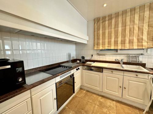 une cuisine avec des armoires blanches et un évier dans l'établissement Cannes Croisette - Appartement 5 pièces face mer, à Cannes