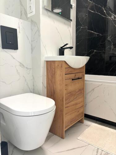 a bathroom with a white toilet and a sink at Olo Apartment in Warsaw