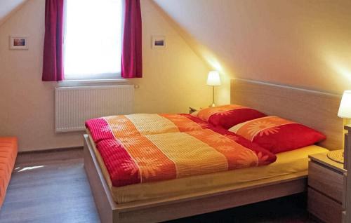 a bedroom with a bed with two red pillows at 1 Bedroom Lovely Apartment In Dierhagen ostseebad in Neuhaus