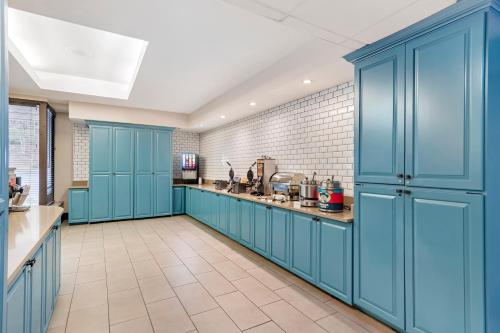 a kitchen with blue cabinets and a tile wall at Country Inn & Suites by Radisson, Atlanta Galleria-Ballpark, GA in Atlanta