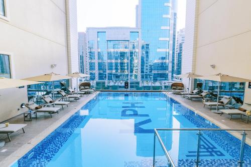 Khalidia Palace Hotel Dubai by Mourouj Gloria في دبي: مسبح كبير في مبنى كبير مع كراسي
