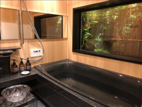 een grote zwarte badkuip in een badkamer met een aquarium bij Kamozen Kyoto Machiya Stay in Kyoto