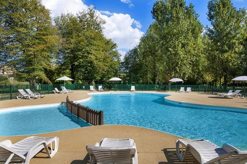 une grande piscine avec chaises et parasols dans l'établissement Camping les Borgnes Saint-Sozy, à Saint-Sozy