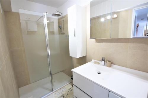 La salle de bains est pourvue d'une douche et d'un lavabo blanc. dans l'établissement AMAZING SEA VIEW APARTMENT, à Cannes