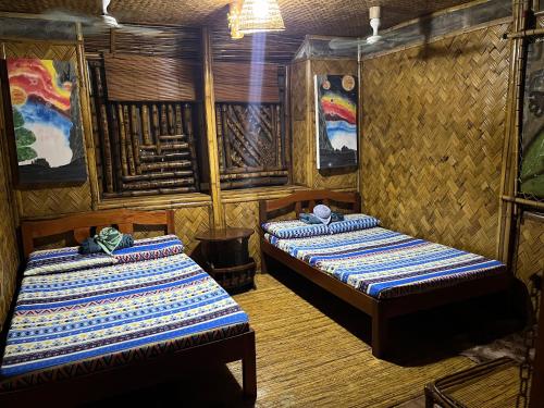 two beds in a room with paintings on the walls at Bamboo Nest in Puerto Princesa City