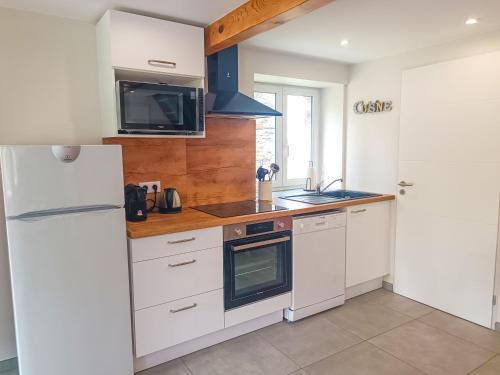 a kitchen with a white refrigerator and a sink at Le gîte d'Ouillon in Saint-Hostien