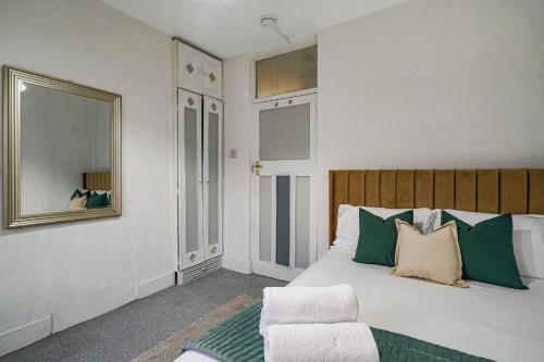 a bedroom with a bed with green and white pillows at Livestay-Two Bedroom Apartment in Clapham in London