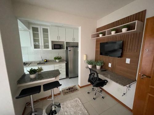 een keuken met witte kasten en zwarte stoelen. bij Apartamento 1 quarto com garagem in Ponta Grossa