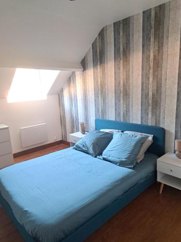 Dormitorio con cama azul y pared a rayas en Gite - Le sachouliot, en Haybes