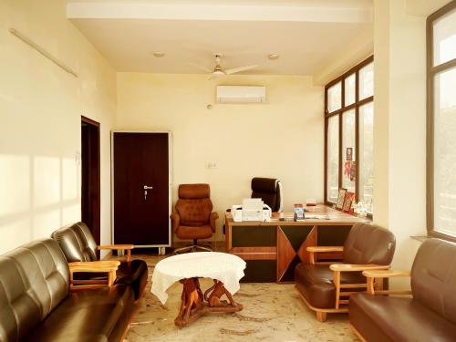 ein Büro mit einem Sofa, einem Schreibtisch und einem Stuhl in der Unterkunft Hotel In North Campus in Neu-Delhi