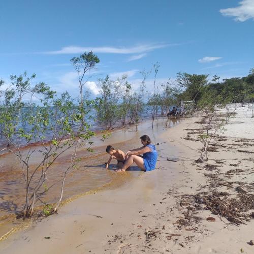 a man and a woman sitting on a beach at POUSADA DA DRI LODGE in Iranduba