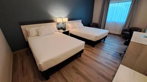 a hotel room with two beds and a desk at Hotel Diego de Almagro Pudahuel Aeropuerto in Santiago