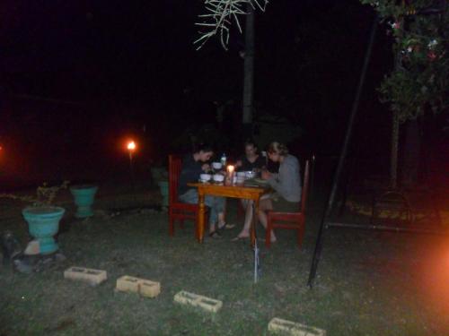un grupo de personas sentadas en una mesa por la noche en Walawe Park View Hotel, en Udawalawe