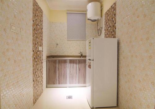 a kitchen with a white refrigerator in a room at هذا منزلي الحمرا in Riyadh