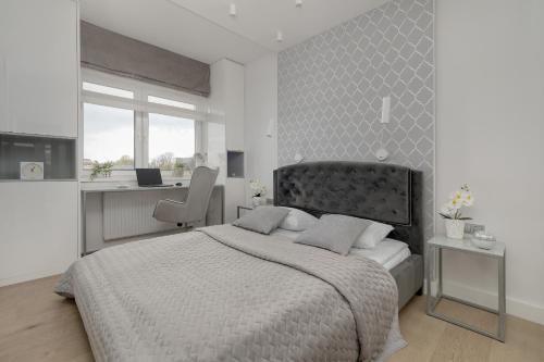 een witte slaapkamer met een bed en een bureau bij Elegant Apartment with Balcony Near Poniatowski Park Łódź by Renters in Łódź