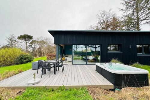 une maison noire avec une terrasse et un bain à remous dans l'établissement Lodge Aigrette - Laïta Guidel, à Guidel