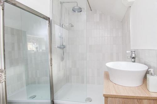 ein weißes Bad mit einer Dusche und einem Waschbecken in der Unterkunft Millstone Cottage Newmillerdam in Hill Top