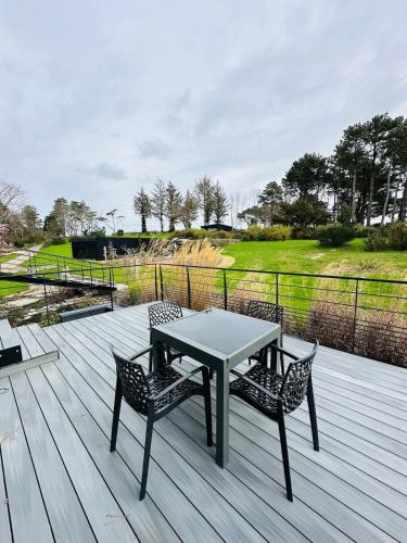 une table et deux chaises sur une terrasse en bois dans l'établissement Avocette élégante - Laïta Guidel, à Guidel